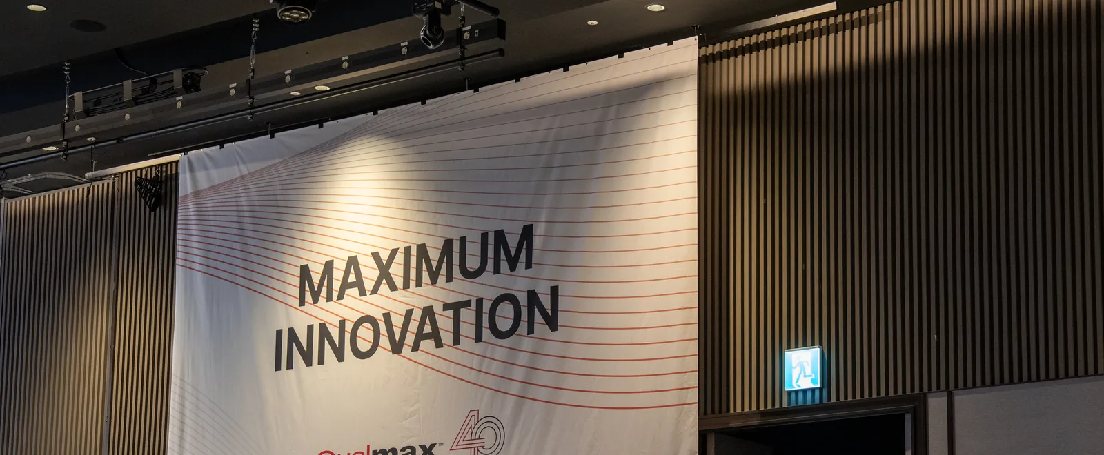 연회장 벽에 건 MAXIMUM INNOVATION 현수막 — 키비주얼의 붉은 선을 이어 씀